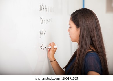 Female High School Student Solving A Math Equation On A White Board