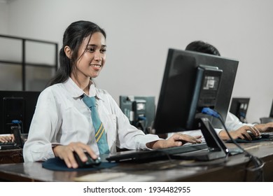 female high school students smile while using a computer pc with their friends