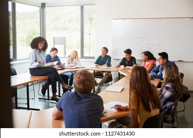 Female High School Tutor Sitting At Table With Pupils Teaching Maths Class - Shutterstock ID 1127431430