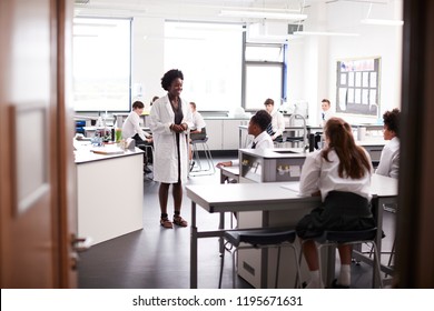 Female High School Tutor Teaching High School Students Wearing Uniforms In Science Class