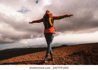 Female hiker with arms spread on mountain peak - exhilaration and wide landscape