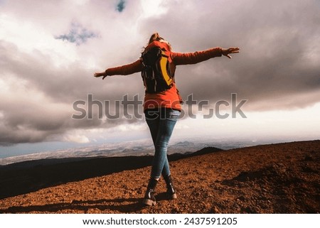 Female hiker with arms spread on mountain peak - exhilaration and wide landscape