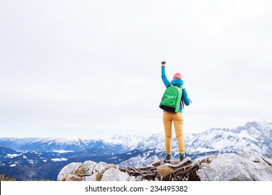 Female hiker with backpack raised her hands celebrating successful climb to top of mountain - Powered by Shutterstock