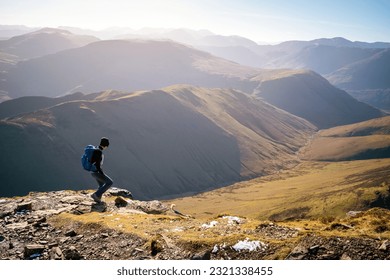 A female hiker descending a rocky path towards Sail from Crag Hill with the summits of High Snockrigg and Robinson in winter in the English Lake District, UK. - Powered by Shutterstock