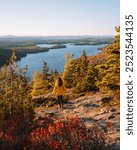 Female Hiker Epic View on Rock Edge in Acadia National Park Sunrise Beech Mountain Beautiful Wide Landscape During Fall Foliage in Maine Yellow Coat