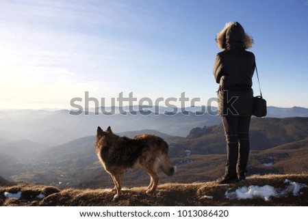 female hiker and his dog looking horizon from ligurian apennines in a sunny day