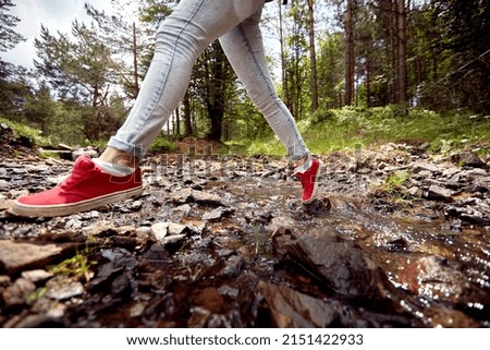 Female hiker jumping over an obstacle while exploring the woods