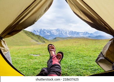 Female hiker llying in tent with a view of mountain 