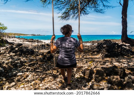 Female Hiker on Rope Swing Under The Shade of Kiawe Trees on Awakee Bay, Kekaha State Park, Hawaii Island, Hawaii, USA