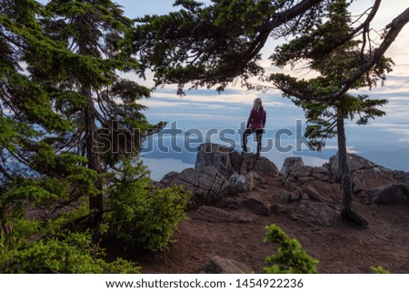 Female Hiker on top of a mountain covered in clouds during a vibrant summer sunset. Taken on top of St Mark's Summit, West Vancouver, British Columbia, Canada.