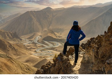 A female hiker stands at the peak and look down