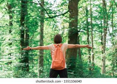 Female hiker with wide spread hands in forest, rear view of woman enjoying outdoor pursuit