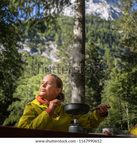 Female hiker/climber preparing supper on gas burner in a camp