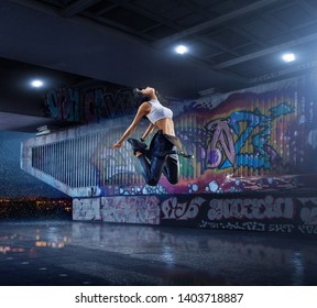 Female Hip Hop Dancer. Beautiful Girl Dancing At Night On The Background Of Graffiti Wall