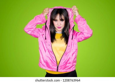 Female Hip Hop Dancer Pulling A Hood Of Jacket Over Her Head While Standing In The Studio With Green Screen