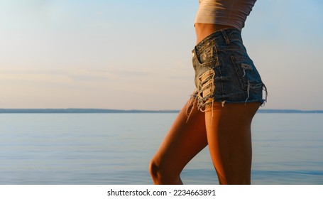 Female hips and belly with bronze tan skin on the beach at sunset