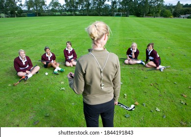 Female hockey coach standing before a team of teenage girls discussing strategy for the game. - Powered by Shutterstock