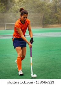 Female Hockey Player Exercising On A Grass Field.