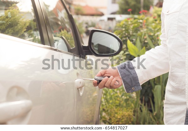 Female holding car\
keys opening car door.