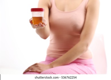 Female Holding Container Of Urine Sample Cup In Hand