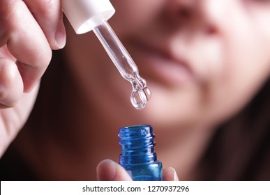 Female Holding Dropper Bottle In Hand