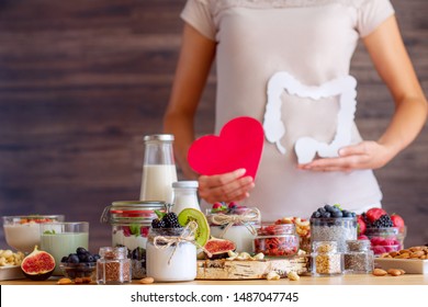 Female is holding figures of heart and intestines. Summer breakfast with organic yogurts fruits, berries and nuts. Nutrition that promotes good digestion and functioning of gastrointestinal tract. - Shutterstock ID 1487047745