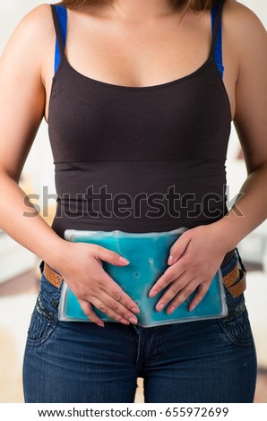 Female holding ice gel pack on her belly , medical concept, in office background
