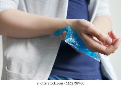 Female Holding Ice Pack To Spot Of Wrist Ache Hand Holding Ice Gel Pack On Swollen Wrist.                     