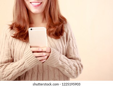 Female holding mobile phone in front of solid background