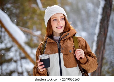 female holding mug of tea. redhead lady drink from thermo mug of coffee in nature. Warm up in frozen winter forest, warm hands. travel, wanderlust, Winter hike. Outdoor recreation on frosty day. - Powered by Shutterstock