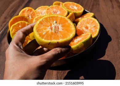 Female holding plate of half Cut Orange, Malta fruits sliced in to half to take out juice