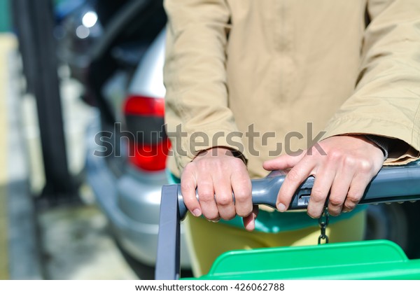 Female holding shopping push cart closeup\
picture of hands with car on\
background