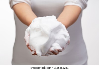 Female Holding Soap Bubbles On White Background. Hands With White Bubbles. Texture Of White Soap Foam On Female Hand.