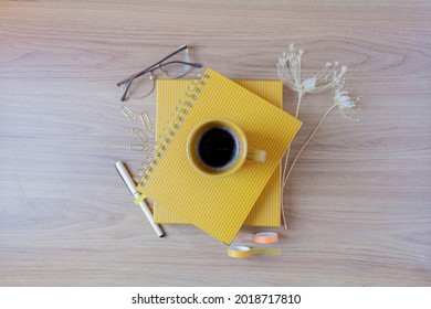 Female Home Office Desk Workspace With A Cup Of Coffee, A Planner, Glasses, Pen, Washi Tapes, Wild Flowers And A Box On Wooden Table. Flat Lay, Top View. Lifestyle Blog, Social Media Composition.