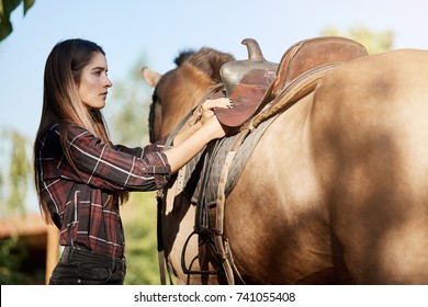 Female Horse Trainer Preparing The Saddle To Have A Ride On A Ranch On A Sunny Autumn Day Dreaming About Prairies