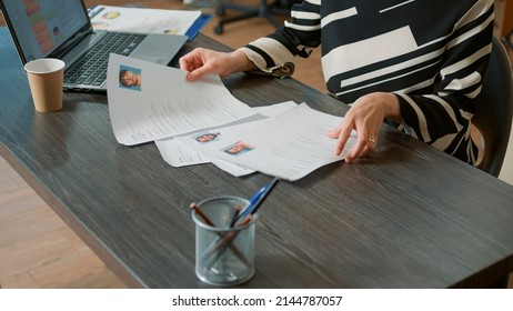 Female HR employee looking at cv resume to hire candidates, analyzing information before job interview. Woman using expertise documents to make job offer and recruit applicants. Close up.
