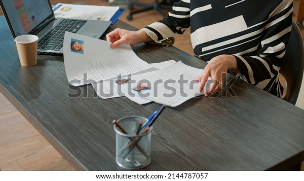 Female HR employee looking at cv resume to hire\
candidates, analyzing information before job interview. Woman using\
expertise documents to make job offer and recruit applicants. Close\
up.