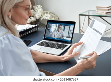 Female hr reading cv during online virtual job interview by video call. Employer checking african male recruit resume talking by distance remote recruitment chat meeting video conference on laptop.