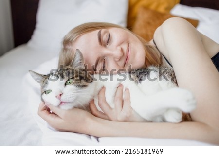 Female hugging cat in hands on the bed at home. Stay home stay safe. Love, care, adoption