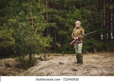 Female hunter in camouflage clothes ready to hunt, holding gun and walking in forest. hunting and people concept