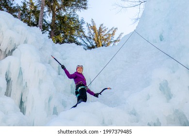 Female Ice Climber Silhouette Swinging Axes Into The Ice With Force, The Shattered Ice Falling