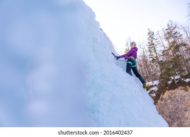 Female Ice Climber Silhouette Swinging Axes Into The Ice With Force, The Shattered Ice Falling