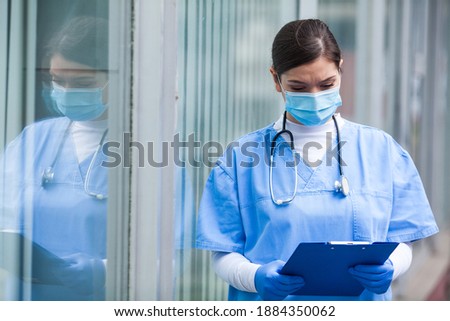Female ICU doctor checking patient medical record clipboard card form,first responder frontline key medical worker,emergency triage service during COVID-19 coronavirus pandemic crisis,outside hospital Foto stock © 