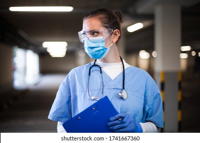 Female ICU doctor in hospital parking lot,first responder frontline key medical worker,holding clipboard patient medical card,looking away,emergency service during COVID-19 coronavirus pandemic crisis
