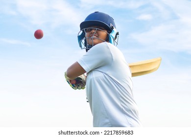 Female Indian cricket player wearing protective gear and hitting the ball with a bat on the field - Shutterstock ID 2217859683