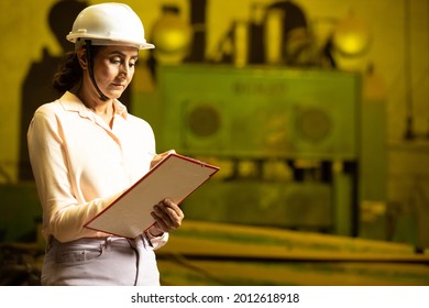 Female Indian Engineer Manager  Or Worker Wearing White Hard Hat Or Helmet Making Notes Working In Industrial Factory. Skill India, Women Empowerment. Copy Space, Background  