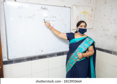 Female Indian Teacher Wearing Mask And Saree Teach Math On Whiteboard In Classroom, School Education Class During Covid19 Pandemic, New Normal,  New Strain Of Coronavirus, Copy Space, Omicron Cases 