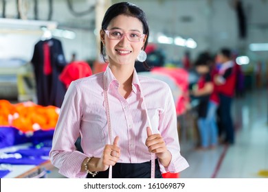 Female Indonesian tailor, dressmaker or designer standing proudly in an Asian textile factory, it is her workplace - Powered by Shutterstock