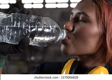 Female Industrial Engineer Drinking Water From Bottle During Work Break - Diverse Engineering Worker Dehydrated In Hot Manufacturing Factory - Regulations, Staff Wellbeing, Health And Safety Concepts