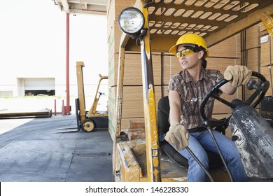 Female Industrial Worker Looking Away While Driving Forklift Truck